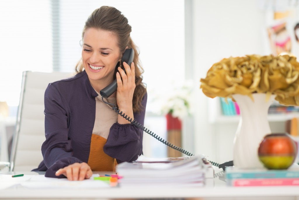 Happy woman talking phone in office