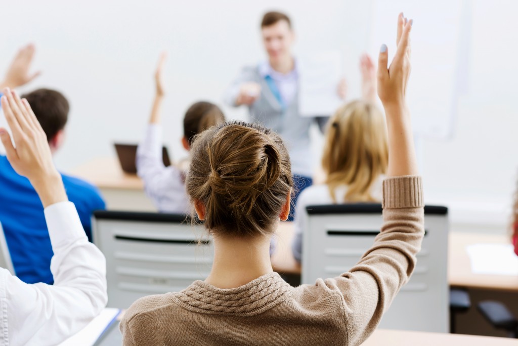 A woman raising her hand in a classroom of employees